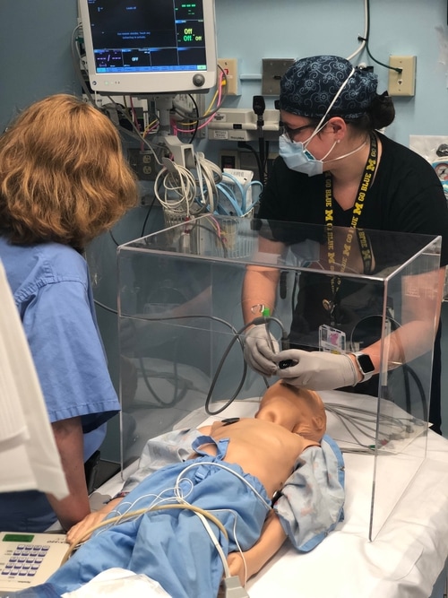 two hospital workers practicing on a mannequin