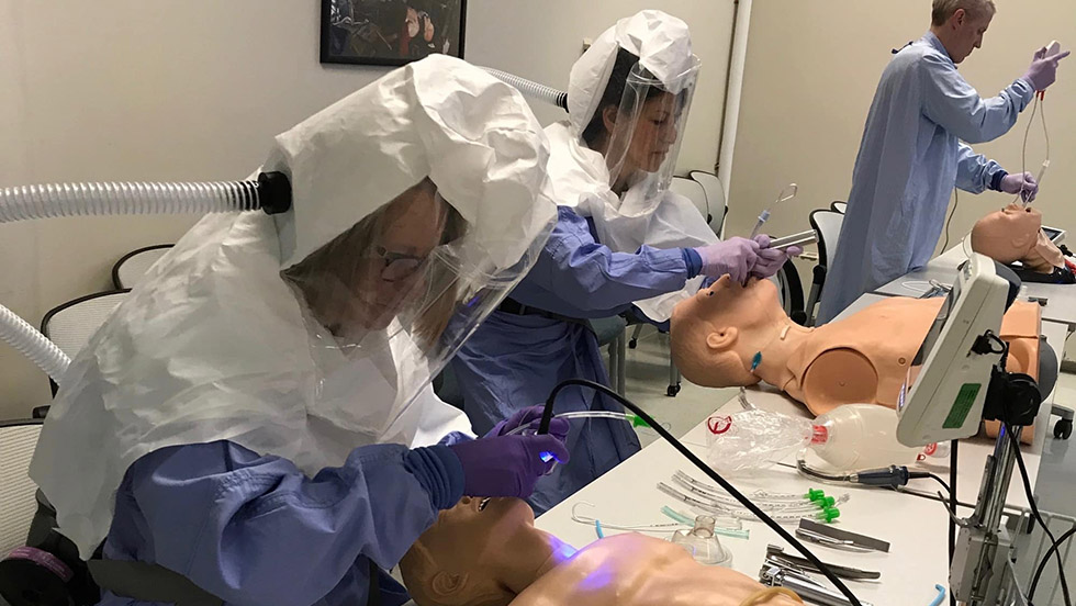 people in Hazmat suits working on model patients